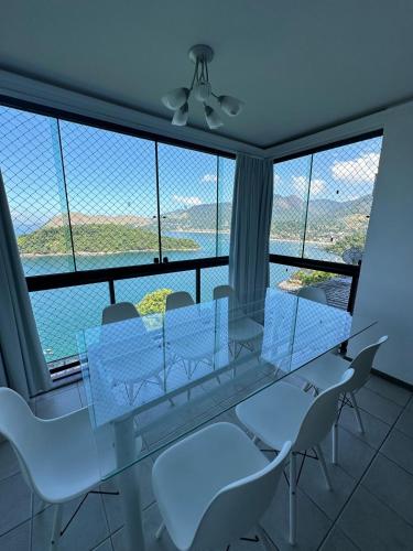a glass table and chairs in a room with a large window at Apartamento maravilhoso em Mangaratiba RJ in Mangaratiba