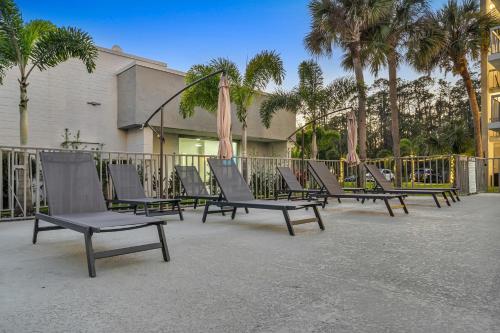 a row of lounge chairs with umbrellas and palm trees at The irlo in Kissimmee