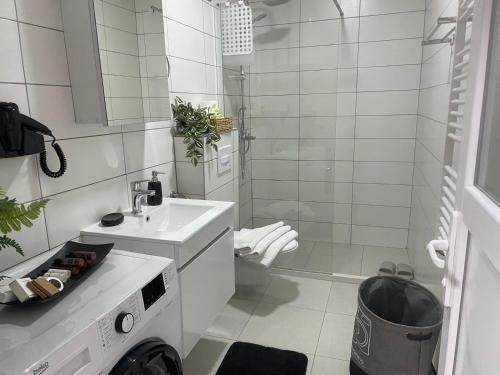 a white bathroom with a sink and a shower at Apartment Prizreni-Free Private Parking in Prizren