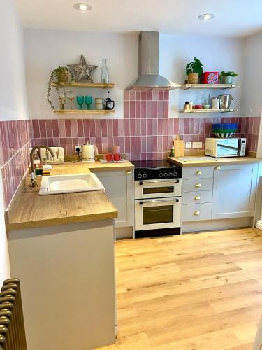 a kitchen with white appliances and pink tiles at No 3, apartment in the heart of Bridport, Dorset in Bridport