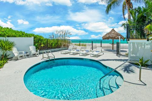 a swimming pool on a patio with a view of the ocean at Seabreeze at Anna Maria Island Inn in Bradenton Beach