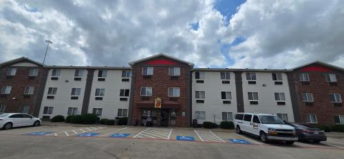 a large building with a white van parked in a parking lot at Super 8 by Wyndham Irving DFW Airport/South in Irving