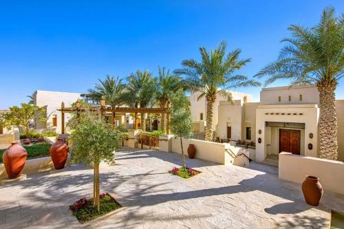 a courtyard with palm trees and a building at Al Wathba, a Luxury Collection Desert Resort & Spa, Abu Dhabi in Abu Dhabi