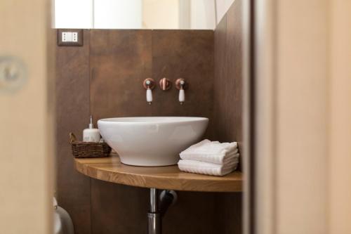 uma casa de banho com um lavatório branco numa prateleira de madeira em La Casa Di Gio' em Matera