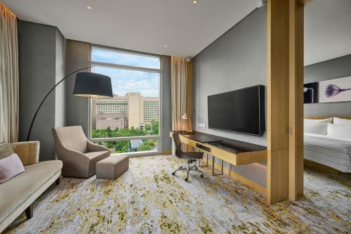 a hotel room with a desk with a television and a bed at Le Meridien Taipei in Taipei