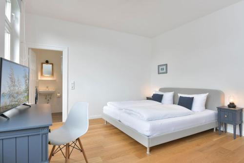 Un dormitorio blanco con una cama blanca y un escritorio. en Dat Ferienhus Klönen, en Gremsmühlen