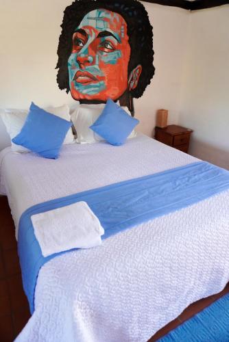 a bed with a painting of a face on the wall at Samariwasi Airport hotel in Yaruqui