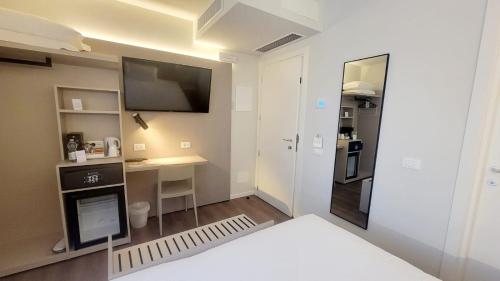 a room with a bed and a television and a desk at Hotel Aurora Duino in Duino