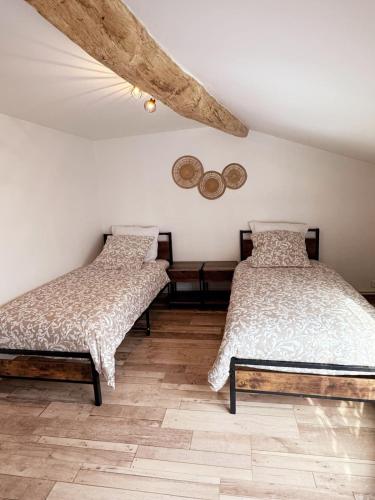 a bedroom with two beds and a wooden floor at L'écrin des Forges maison cosy 1 à 6 voyageurs in Cousancelles