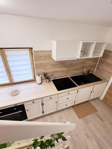 a kitchen with white cabinets and a sink at L'écrin des Forges maison cosy 1 à 6 voyageurs in Cousancelles