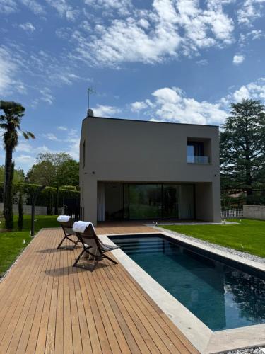 a house with a pool and a chair on a wooden deck at Exclusive Villa Perla & swimming pool in Bovezzo