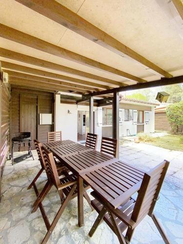 une table et des chaises en bois sur une terrasse dans l'établissement Résidence Het Club - Charmante maison avec jardin dans la pinède pour 6 personnes à Lacanau Océan MAE-0401, à Lacanau