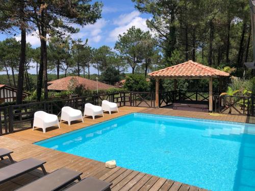 une piscine avec des chaises et un gazebo dans l'établissement Villa de l'océan, à Moliets-et-Maa