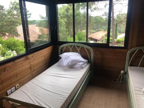Cette petite chambre comprend 2 lits et 2 fenêtres. dans l'établissement Villa de l'océan, à Moliets-et-Maa