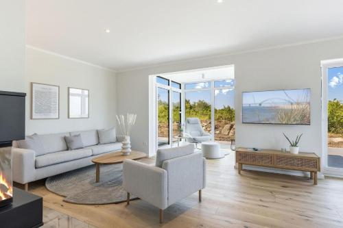 a living room with white furniture and a fireplace at Ferienhaus De Bööi 9253 in Westermarkelsdorf