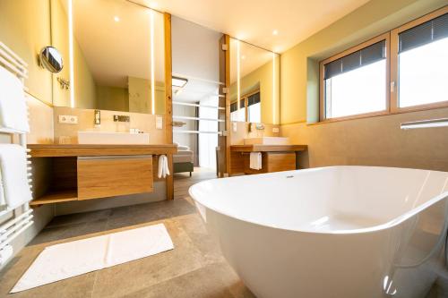 a large bathroom with a tub and a large mirror at Ferienwohnungen Fasching - Ferienapartments Weitblick in Fischbach