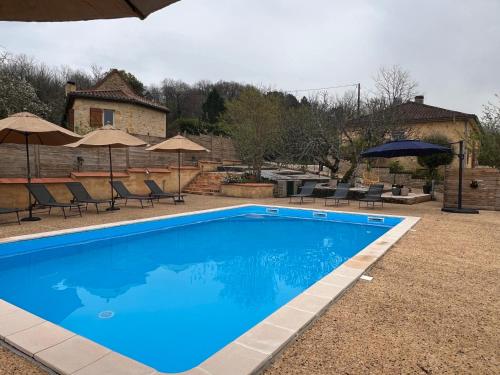 une piscine bleue avec des chaises et des parasols dans l'établissement Blue Horizons Farm, à Sarlat-la-Canéda