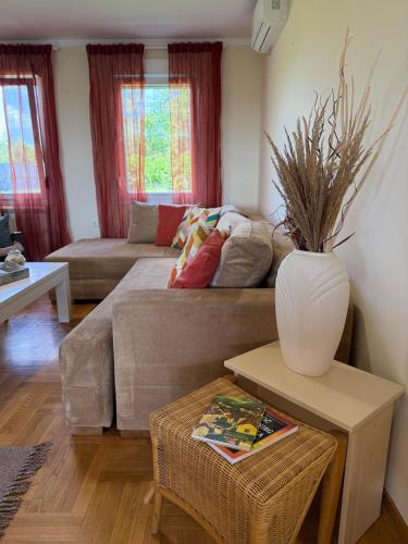 a living room with a couch and a vase on a table at Zen Cherry House- Vikendica na dan sa bazenom1,5ha izmedju Avale i Kosmaja in Drobnjaci
