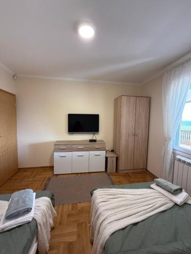 a bedroom with two beds and a flat screen tv at Zen Cherry House- Vikendica na dan sa bazenom1,5ha izmedju Avale i Kosmaja in Drobnjaci
