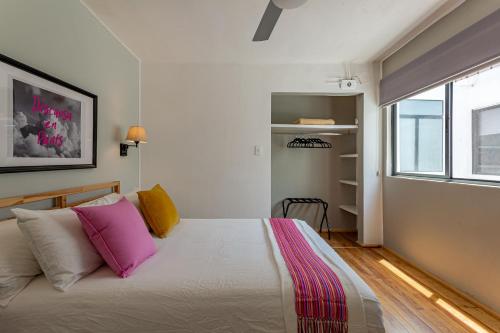 a bedroom with a bed with pink and yellow pillows at Amalli, Refugio Urbano in Mexico City