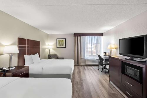 a hotel room with a bed and a desk with a television at Best Western Luxbury Inn Fort Wayne in Fort Wayne