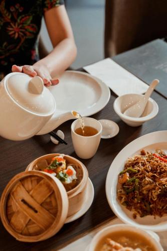 a table with plates of food and a tea pot at AC Hotel by Marriott Ipoh in Ipoh