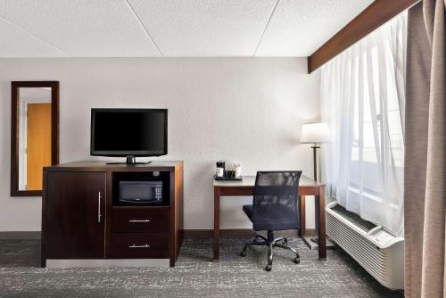 a hotel room with a desk with a tv and a chair at Best Western Luxbury Inn Fort Wayne in Fort Wayne