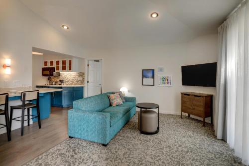 a living room with a blue couch and a kitchen at Sonesta ES Suites San Jose - Airport in San Jose