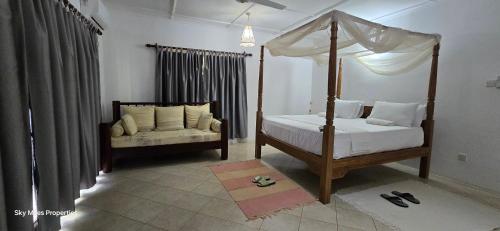 a bedroom with a four poster bed and a couch at Jasmin Villa in Mtwapa