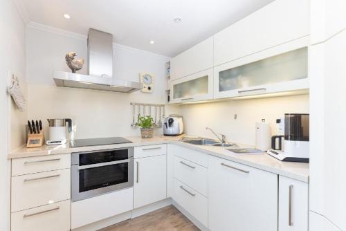 a white kitchen with white cabinets and appliances at Buhne 3 in Grömitz