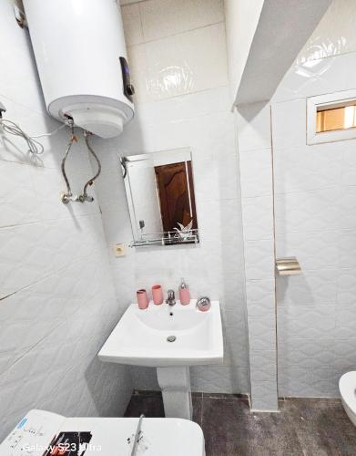 ein weißes Badezimmer mit Waschbecken und Spiegel in der Unterkunft Elykia in Kinshasa