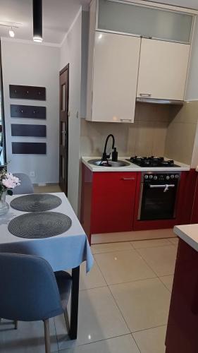 cocina con armarios rojos, mesa y fogones en Apartament Park Podzamcze, en Olsztyn
