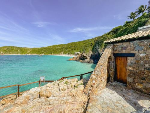 a stone building next to a body of water at Hotel Recanto do Atalaia in Arraial do Cabo