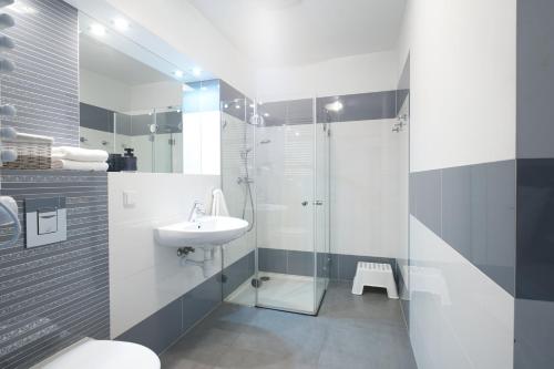 een badkamer met een glazen douche en een wastafel bij Apartamenty Olimpic in Kołobrzeg