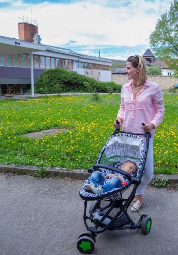 a woman pushing a baby in a stroller at Tündérkert Hotel Noszvaj in Noszvaj