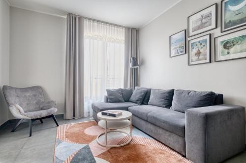 Una sala de estar con un sofá gris y una silla. en Apartamenty Olimpic, en Kołobrzeg