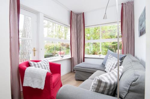 een woonkamer met een rode bank en een raam bij Ferienhaus am Strandwäldchen in Timmendorfer Strand