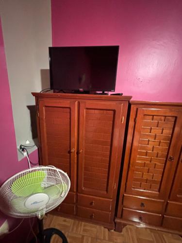 a television on top of a wooden cabinet with a chair at Hotel Posada "Mi Rosita" in Oaxaca City