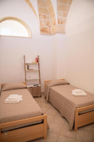 two beds in a white room with a window at Mesciu Bruno Casa Vacanza in Copertino