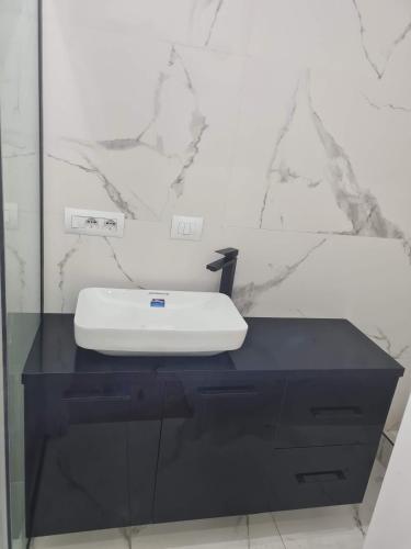 a bathroom with a white sink on a black counter at Topfix in Korçë