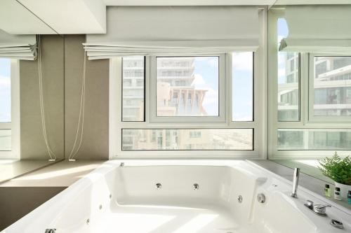 a white bath tub in a room with windows at Trumpeldor 1 - Luxury Beach Apartments Hotel - By Vacay in Tel Aviv