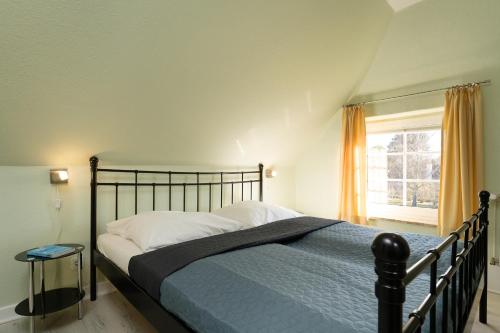 a bedroom with a bed with a blue blanket and a window at Villa FarbenFroh in Fehmarn