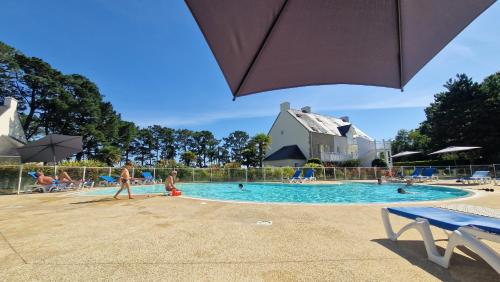 - un groupe de personnes dans une piscine avec un parasol dans l'établissement CAP COZ plage piscine et jardin, à Fouesnant