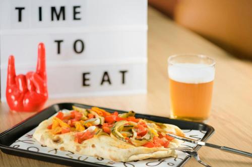 a pizza on a plate next to a glass of beer at Moxy Pompeii in Torre Annunziata