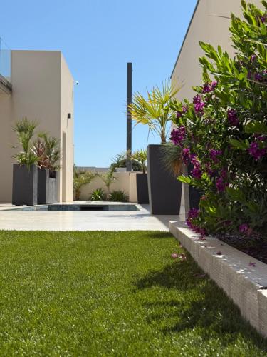 a yard with green grass and purple flowers at La villa Kalima T3 in Sérignan