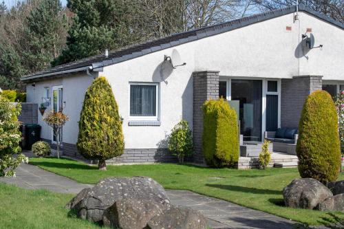 a white house with bushes in front of it at Beautiful attractive house free parking near Airport in Edinburgh