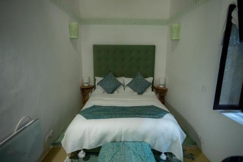 a small bedroom with a bed with a green headboard at Dar Lalzohra in Rabat