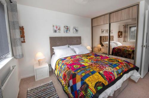 a bedroom with a large bed with a colorful quilt at Beautiful attractive house free parking near Airport in Edinburgh