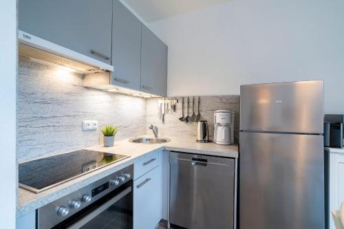a kitchen with white cabinets and a stainless steel refrigerator at Alte Bergstraße 6 Sehnsucht in Scharbeutz
