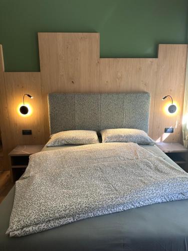 a bedroom with a large bed with two lamps at Agritur Leita in Tuenno